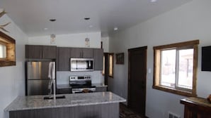 Cozinha moderna com ilha central, eletrodomésticos de aço inoxidável e uma grande janela que oferece iluminação natural.