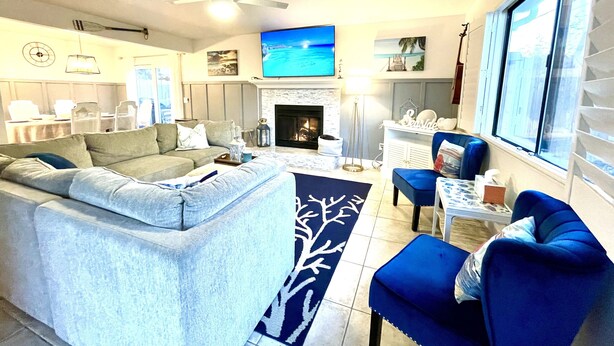 A modern living room with a fireplace, a large TV, and a dining area with chairs and a table.