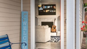 A front porch with a blue bench, a welcome sign, and a number '445' on the wall.