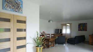 A spacious living area with a dining table, chairs, a sofa, and a TV. - Modern holiday home with heated pool (Pradons)