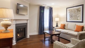 Una sala de estar con chimenea, un sofá, una mesa de centro y un televisor.