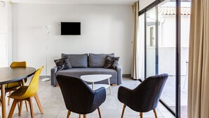 A modern living room with a sofa, two armchairs, a small table, and a TV on the wall. - Attractive Holiday Home in Malaucène with Terrace (malaucène)