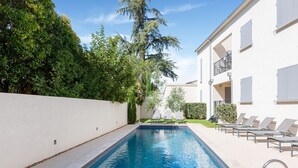 A swimming pool with a white wall and a building with balconies. - Attractive Holiday Home in Malaucène with Terrace (malaucène)