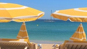 A beach with yellow striped umbrellas and lounge chairs facing the sea. - Farmhouse, with large pvt pool in Provence (Draguignan)