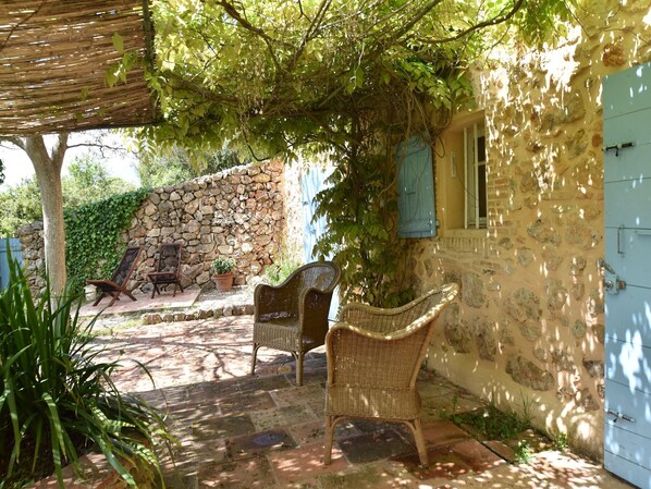 A patio area with wicker furniture, a stone wall, and a blue door.