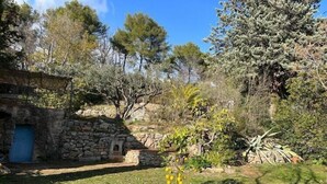 A rustic stone building with a blue door, surrounded by a garden with various plants and trees. - Farmhouse, with large pvt pool in Provence (Draguignan)