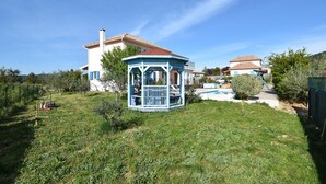 A gazebo in a grassy yard with a house in the background. - Beautiful Villa with Private Swimming Pool in Oupia (Oupia)