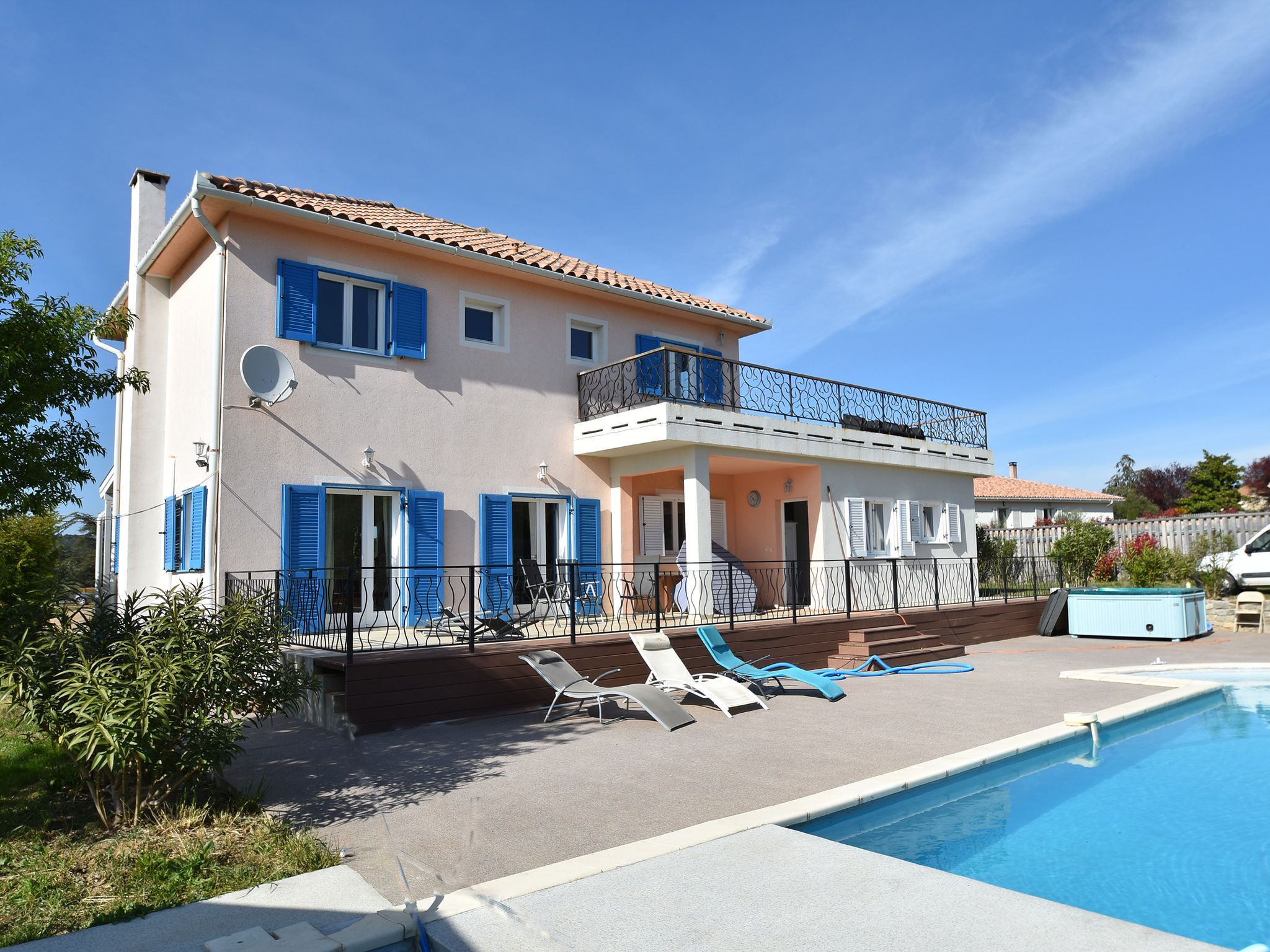 A two-story house with a swimming pool, blue shutters, and a balcony.