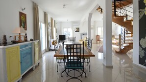 A spacious dining area with a wooden table and chairs, a colorful cabinet, and a staircase leading to an upper level. - Beautiful Villa with Private Swimming Pool in Oupia (Oupia)
