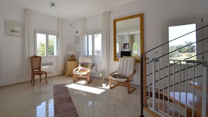 A spacious living room with a large mirror, two wooden chairs, a small table, and a staircase. - Beautiful Villa with Private Swimming Pool in Oupia (Oupia)