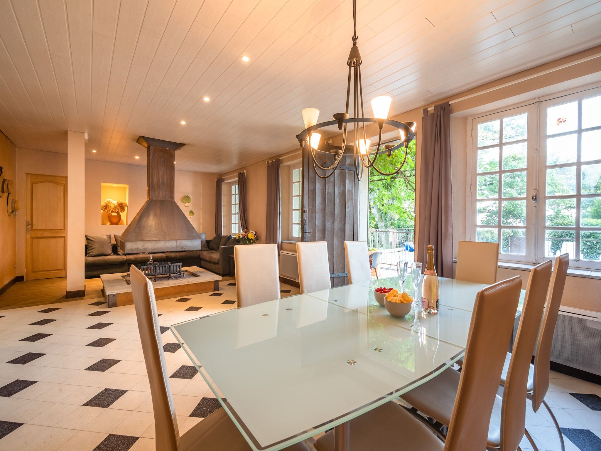 A modern kitchen with a large stove, a dining table with chairs, and a view of greenery outside.