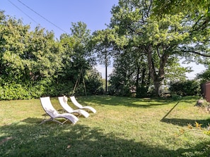 A grassy outdoor area with three white lounge chairs and a swing set. - Stone House St Denis with Pool & Views (Saint Denis)