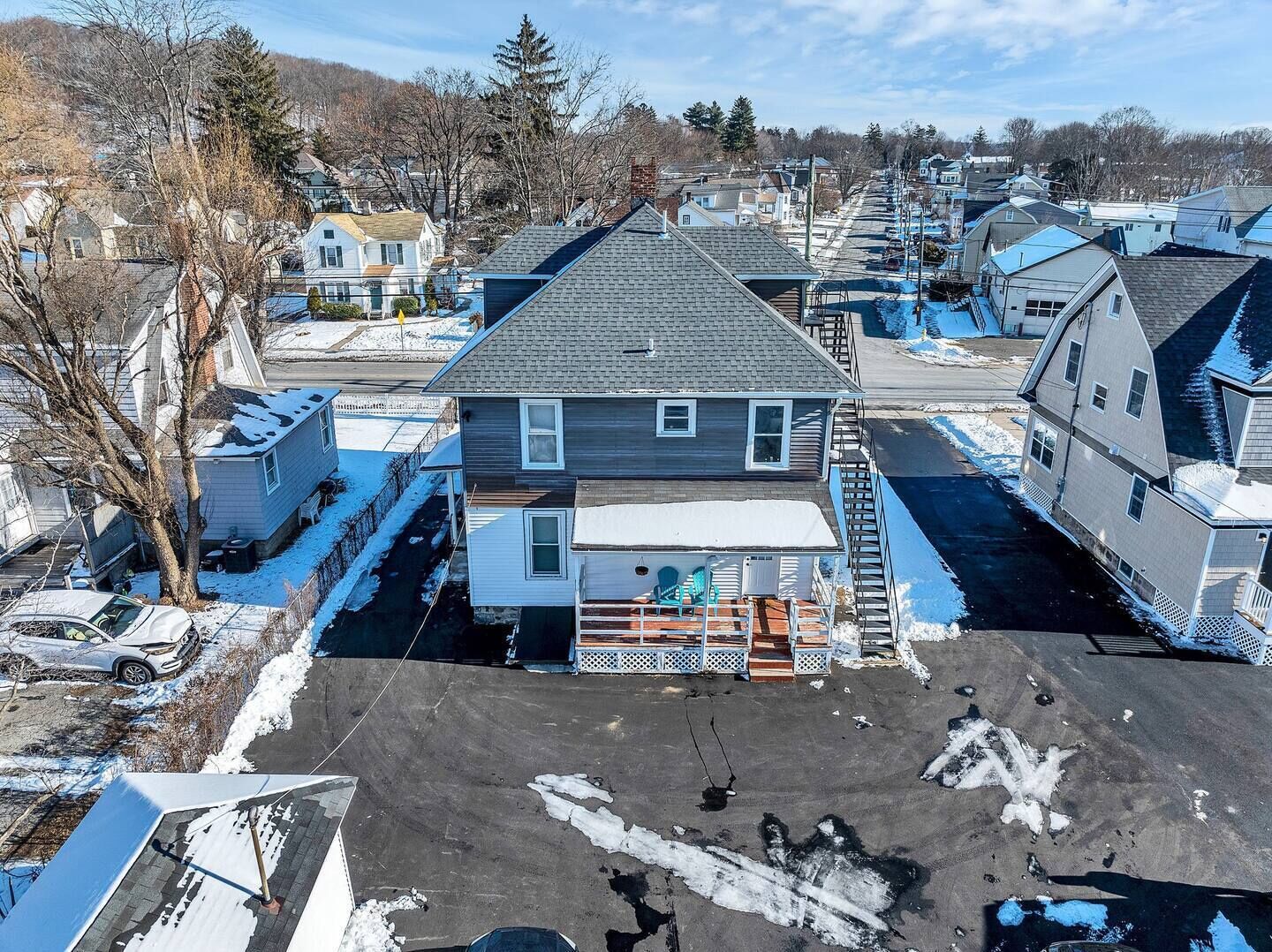 A residential area with houses, a covered deck, and a snow-covered ground.