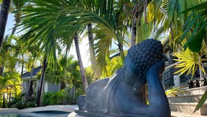 A statue of a sea creature by a pool with palm trees and a building in the background. - Studio Master   Residence Adam et  Eve (Baie Orientale)