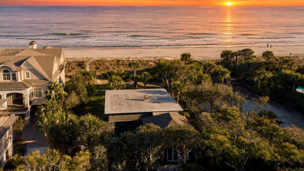 A beachfront property with a large house, a swimming pool, and a view of the ocean at sunset. - Steps to Beach + Historic Cottage | Primary Balcony + Hammock | Sandpiper (Hilton Head Island)