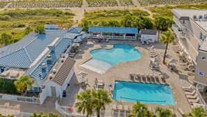 Un complex turístic amb diverses piscines, gandules i una zona de platja.