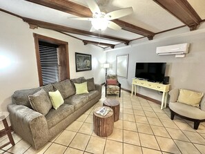 A living room with a grey sofa, a wooden coffee table, a TV, and a ceiling fan.