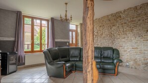 Una sala de estar con un sofá seccional de cuero verde, una pared de piedra y un radiador.