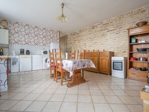 Une cuisine avec un mur en pierre, une table à manger avec des chaises et divers appareils de cuisine.