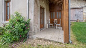 Un edificio rústico con fachada de piedra, un porche de madera y una pequeña mesa con sillas.