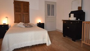 Un dormitorio con cama, dos mesitas de noche con lámparas, cómoda, espejo y puerta.