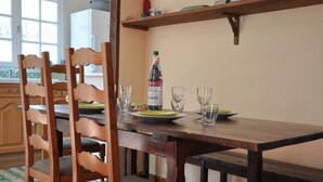 Une table de salle à manger en bois, avec des chaises, une bouteille de vin et des verres posés sur un comptoir de cuisine.
