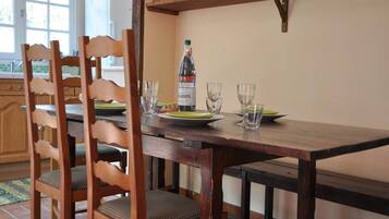 Une table de salle à manger en bois, avec des chaises, une bouteille de vin et des verres posés sur un comptoir de cuisine.