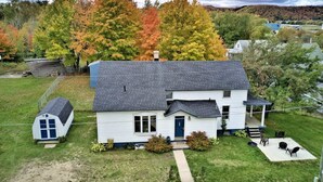 A two-story house with a dark roof, a front porch, and a small attached garage.