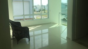 Una habitación amplia con un gran ventanal, una silla negra y un balcón con barandilla.