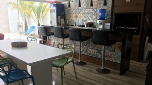 Una cocina moderna con barra, que incluye un salpicadero de azulejos, taburetes de bar y una mesa de comedor con sillas.