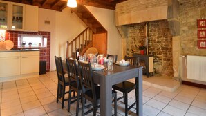 Una cocina rústica con una mesa de comedor para cuatro, vigas de madera en el techo y una pared de piedra con chimenea.