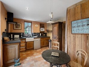 A compact kitchen with wooden cabinets, a black countertop, a sink, a dishwasher, and a dining area with a table and chairs.