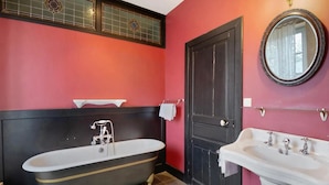 Une salle de bain avec une baignoire, un lavabo, une porte et un miroir.