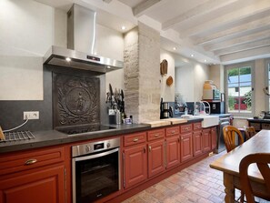 Une cuisine équipée d’un four encastré, d’une cuisinière et d’un grand îlot central agrémenté d’un pare-feu décoratif.