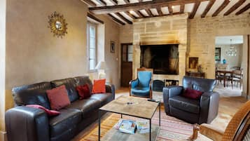 Un salon avec une cheminée, des canapés en cuir et un tapis à motifs.
