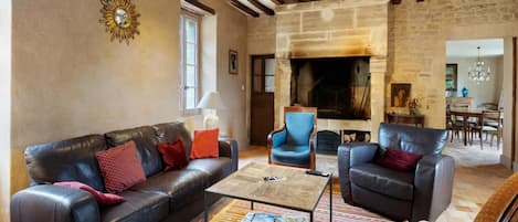 Una sala de estar con chimenea, sofás de cuero y alfombra estampada.