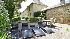A stone building with a gravel patio, outdoor seating, and a garden with lavender. - Elegant Normandy Retreat (Lantheuil)