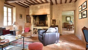 A cozy living room with a fireplace, stone walls, and exposed wooden beams. - Elegant Normandy Retreat (Lantheuil)