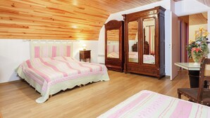 Un dormitorio con techo de madera, un espejo grande, una cama con colcha a rayas rosa y blanca, y un armario de madera.