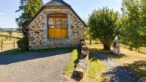 Una cabaña de piedra con puerta de madera, un camino de grava y un muro de piedra con maceta.