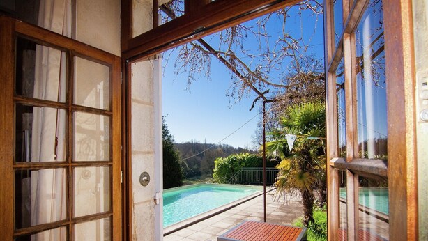 An open door to a patio with a pool, a table, and chairs. - Hilltop Mansion with Pool (Sigoulès)