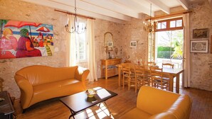 A living room with a sofa, a dining table with chairs, a chandelier, and a painting on the wall. - Hilltop Mansion with Pool (Sigoulès)