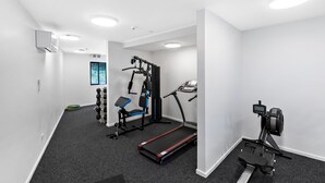 A gym with a treadmill, weight bench, and various exercise machines. - 1 Bedroom Modern Apartment in Queenstown (Queenstown)