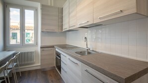 Una cocina moderna con armarios de madera clara, un lavamanos de acero inoxidable y una ventana con vistas a una zona residencial.
