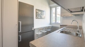 Una cocina moderna con refrigerador integrado, un lavamanos y un ventanal que proporciona luz natural.