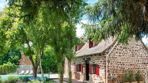 A stone building with a red door and windows, surrounded by greenery and a pool. - Beautiful holiday home with pool in Teillots (Teillots)