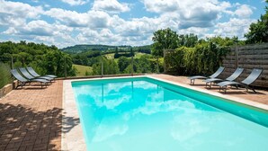 A rectangular swimming pool with clear blue water, surrounded by a brick patio. There are lounge chairs on both sides of the pool. - Beautiful holiday home with pool in Teillots (Teillots)