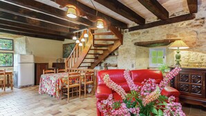A rustic interior with a wooden staircase, a red leather sofa, a dining table with chairs, and a refrigerator. - Holiday Home in Besse by Lake & Forest (Besse)