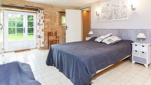 A bedroom with a bed, bedside tables, a chair, a door leading to a balcony, and a wall with a floral painting. - Holiday Home in Besse by Lake & Forest (Besse)
