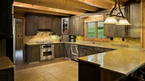 Une cuisine moderne dotée de plans de travail en granit, d’appareils électroménagers en acier inoxydable et de meubles en bois.